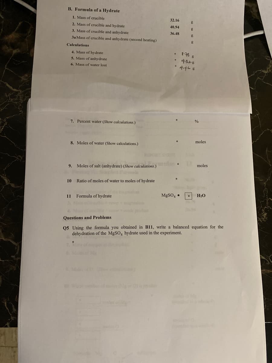 B. Formula of a Hydrate
1. Mass of crucible
32.16
2. Mass of crucible and hydrate
40.94
3. Mass of crucible and anhydrate
g
36,48
3a Mass of crucible and anhydrate (second heating)
Calculations
4. Mass of hydrate
t76 g
5. Mass of anhydrate
4ろと8
6. Mass of water lost
4.468
7. Percent water (Show calculations.)
%
8. Moles of water (Show calculations.)
moles
9. Moles of salt (anhydrate) (Show calculations.)
moles
10
Ratio of moles of water to moles of hydrate
11
Formula of hydrate
MgSO, •
H2O
Questions and Problems
Q5 Using the formula you obtained in B11, write a balanced equation for the
dehydration of the MgSO, hydrate used in the experiment.
