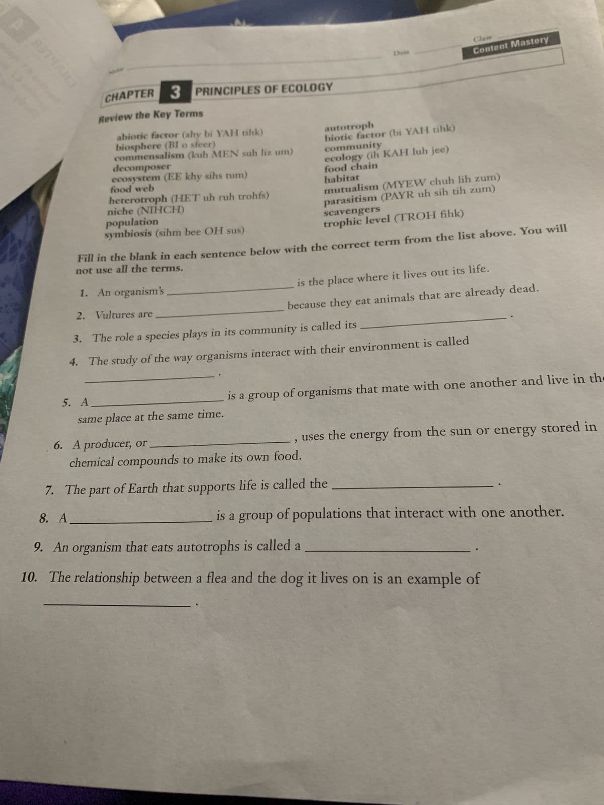 ង. សសរ
PRINCIPLES OF ECOLOGY
CHAPTER 3
Review the Key Terms
5. A.
abiotic factor (ahy bi YAH tihk)
biosphere (BI o sfeer)
commensalism (kuh MEN suh liz um)
decomposer
ecosystem (EE khy sihs tum)
food web
heterotroph (HET uh ruh trohfs)
niche (NIHCH)
population
symbiosis (sihm bee OH sus)
autotroph
biotic factor (bi YAH tihk)
community
ecology (ih KAH luh jee)
food chain
habitat
Fill in the blank in each sentence below with the correct term from the list above. You will
not use all the terms.
same place at the same time.
1. An organism's
2.
Vultures are
The role a species plays in its community is called its
3.
4. The study of the way organisms interact with their environment is called
mutualism (MYEW chuh lih zum)
parasitism (PAYR uh sih tih zum)
scavengers
trophic level (TROH fihk)
Content Mastery
is the place where it lives out its life.
because they eat animals that are already dead.
6. A producer, or
chemical compounds to make its own food.
is a group of organisms that mate with one another and live in the
, uses the energy from the sun or energy stored in
7.
The part of Earth that supports life is called the
8. A
is a group of populations that interact with one another.
9. An organism that eats autotrophs is called a
10. The relationship between a flea and the dog it lives on is an example of