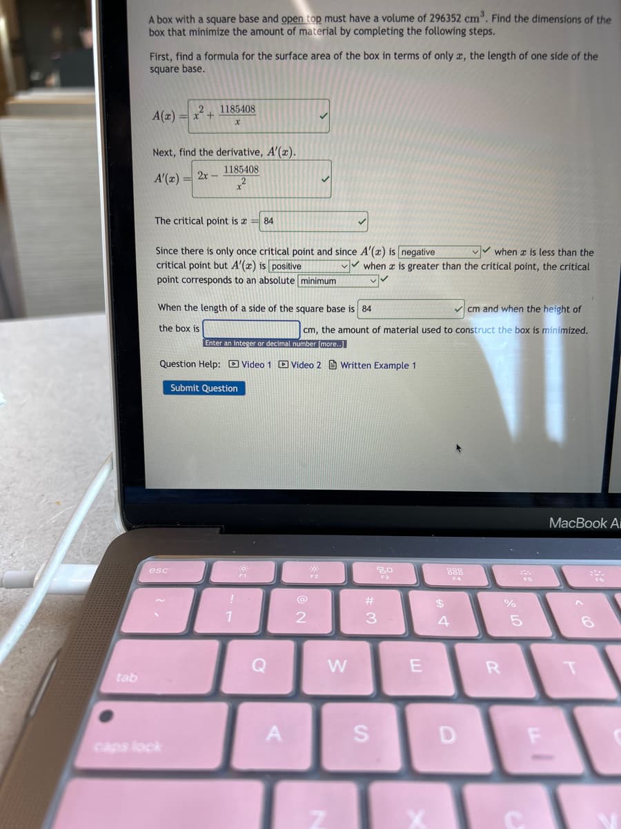 **Problem Statement:**
A box with a square base and open top must have a volume of 296352 cm³. Find the dimensions of the box that minimize the amount of material by completing the following steps.

**Step 1: Find a formula for the surface area of the box in terms of only \( x \), the length of one side of the square base.**

\[ A(x) = x^2 + \frac{1185408}{x} \]

**Step 2: Find the derivative, \( A'(x) \).**

\[ A'(x) = 2x - \frac{1185408}{x^2} \]

**Step 3: Determine the critical point.**
The critical point is \( x = 84 \).

**Step 4: Analyze the behavior of the derivative to determine whether the critical point corresponds to a minimum.**
Since there is only one critical point and since \( A'(x) \) is **negative** when \( x \) is less than the critical point but \( A'(x) \) is **positive** when \( x \) is greater than the critical point, the critical point corresponds to an absolute **minimum**.

**Step 5: Calculate the dimensions when the length of a side of the square base is 84 cm.**

When the length of a side of the square base is \( 84 \) cm and when the height of the box is \( \_\_\_\_\_\_\_\_\_\_\_\_ \) cm, the amount of material used to construct the box is minimized.

**User Input Fields:**
- Enter height of the box in cm: [Input field for user to enter value]
- Submit button

**Resources for Assistance:**
1. Video Help 1
2. Video Help 2
3. Written Example 1

**Submission:**
- Submit Question (Button for submitting the inputted solution)

This structure guides learners through the problem-solving process step-by-step, incorporating calculus concepts such as derivative and critical point analysis to find the optimal dimensions for minimizing the material used for the box.